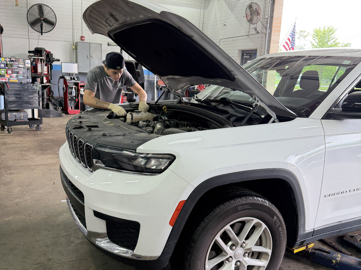 A First Call Auto Care technician working under the hood of a Jeep Grand Cherokee in the Royal Oak shop