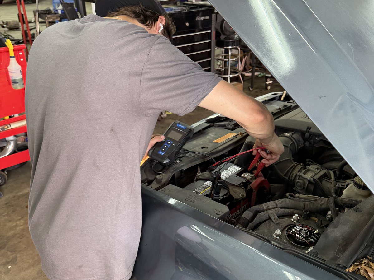 A First Call Auto Care technician testing a vehicle battery with a handheld tester in Royal Oak
