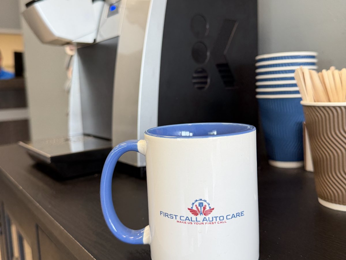 A First Call Auto Care branded mug beside the brewer at the Royal Oak waiting area coffee bar
