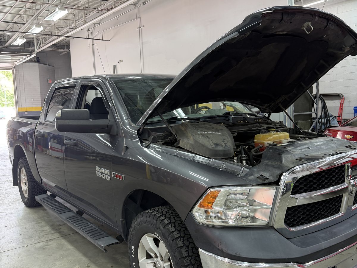 A diesel pickup with the hood raised in a service bay at First Call Auto Care in Royal Oak