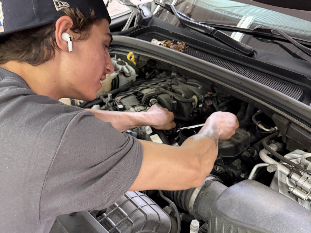 A technician reaching into an engine bay at First Call Auto Care in Royal Oak during fuel system work