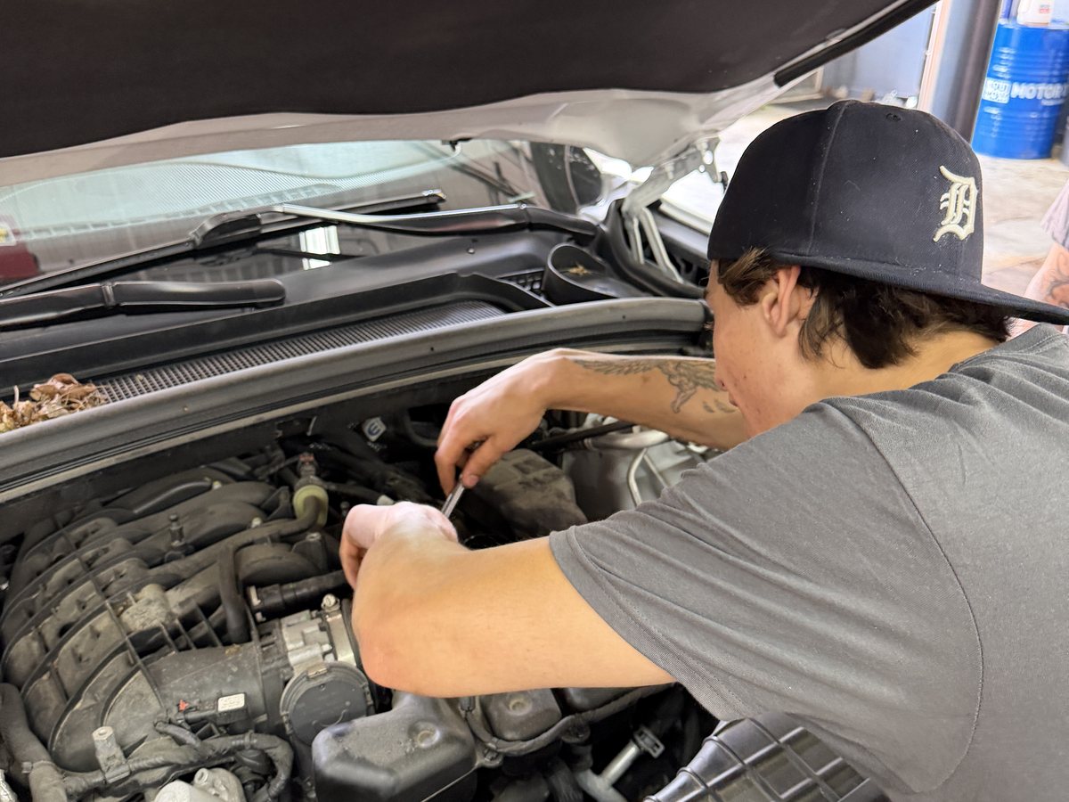 A First Call Auto Care technician working on the fuel and intake components of an engine in Royal Oak