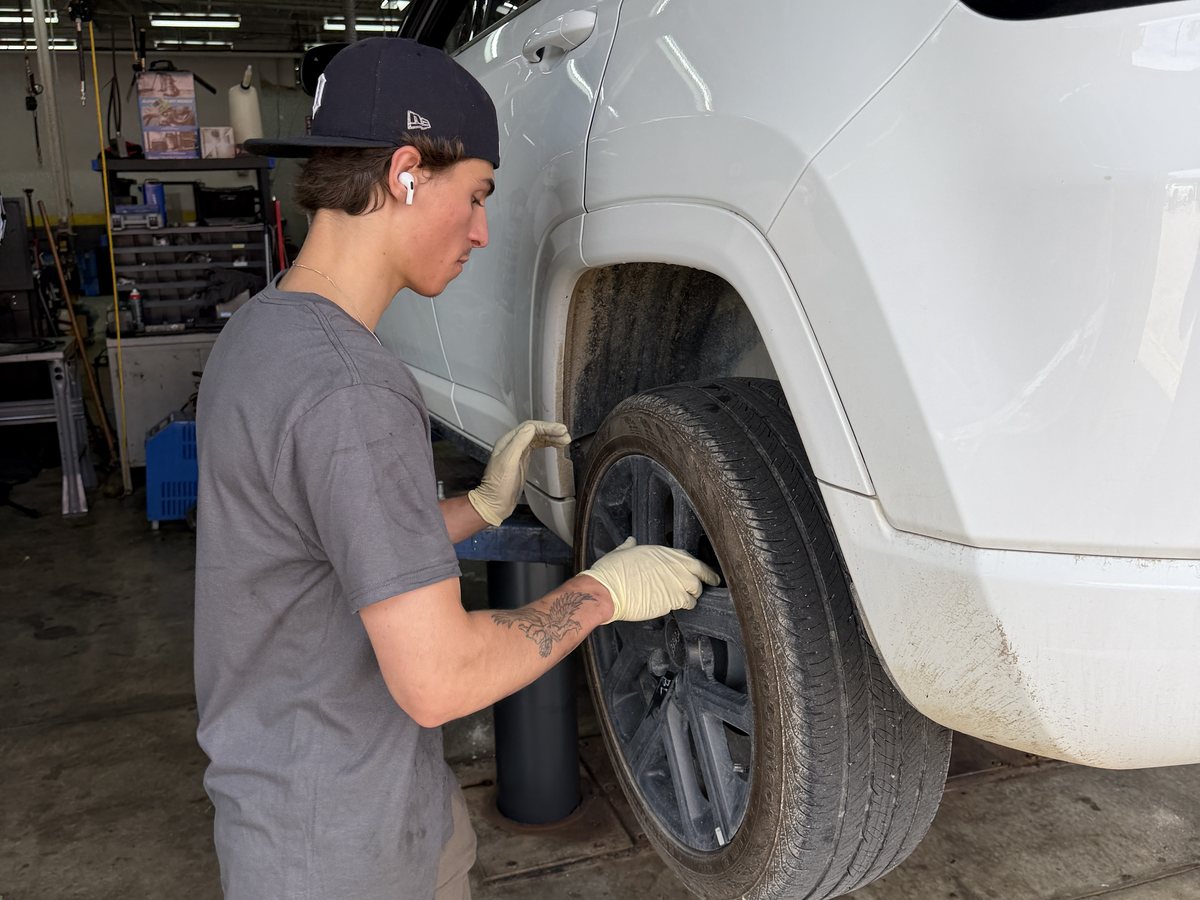 A First Call Auto Care technician taking a wheel off a vehicle raised on a lift at the Royal Oak shop