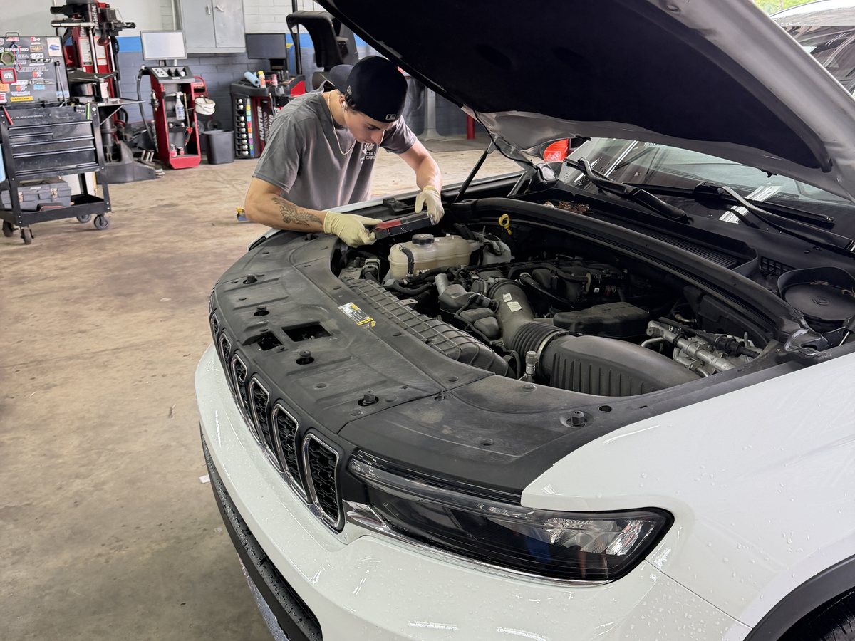A technician checking underneath a vehicle on a lift at First Call Auto Care during a pre-purchase inspection
