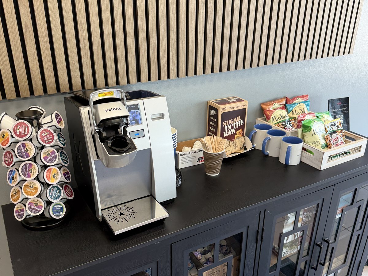 The coffee bar in the customer waiting area at First Call Auto Care in Royal Oak, MI, with a single cup brewer, mugs and snacks
